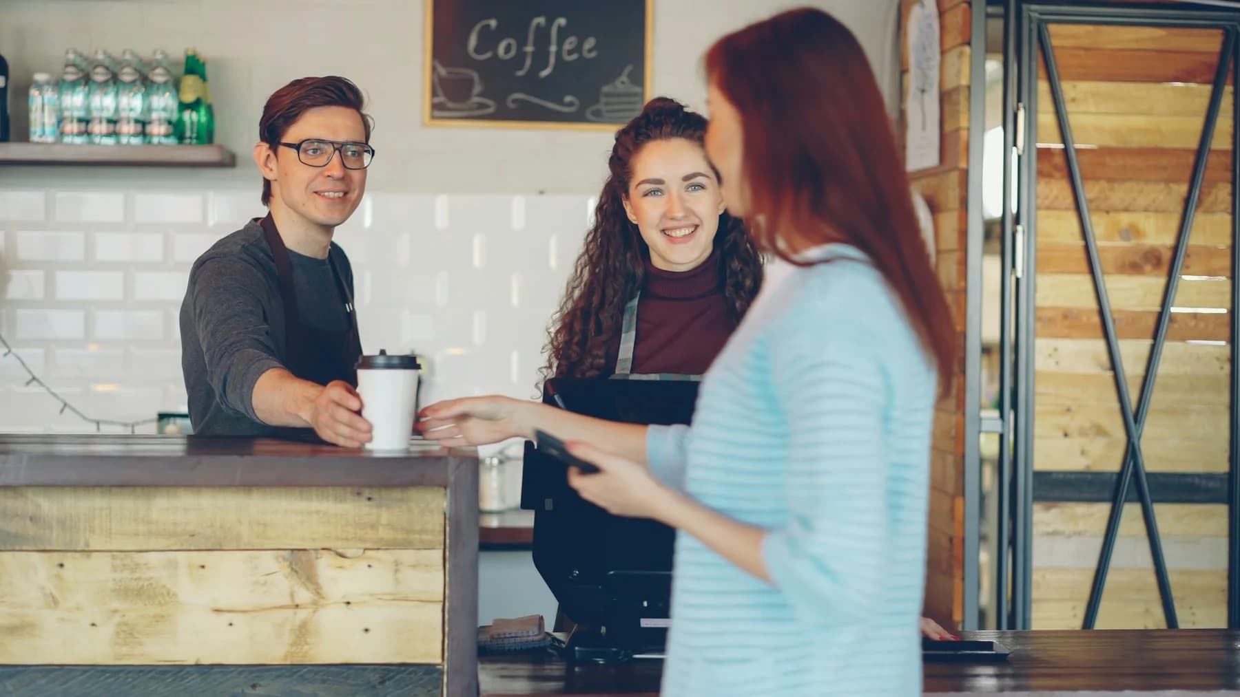 Una clienta recibe su café mientras el equipo atiende detrás de la barra.